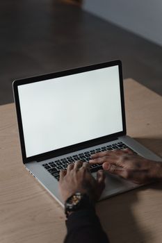 Close-up of hands typing on a blank screen laptop, creating a versatile workspace image.